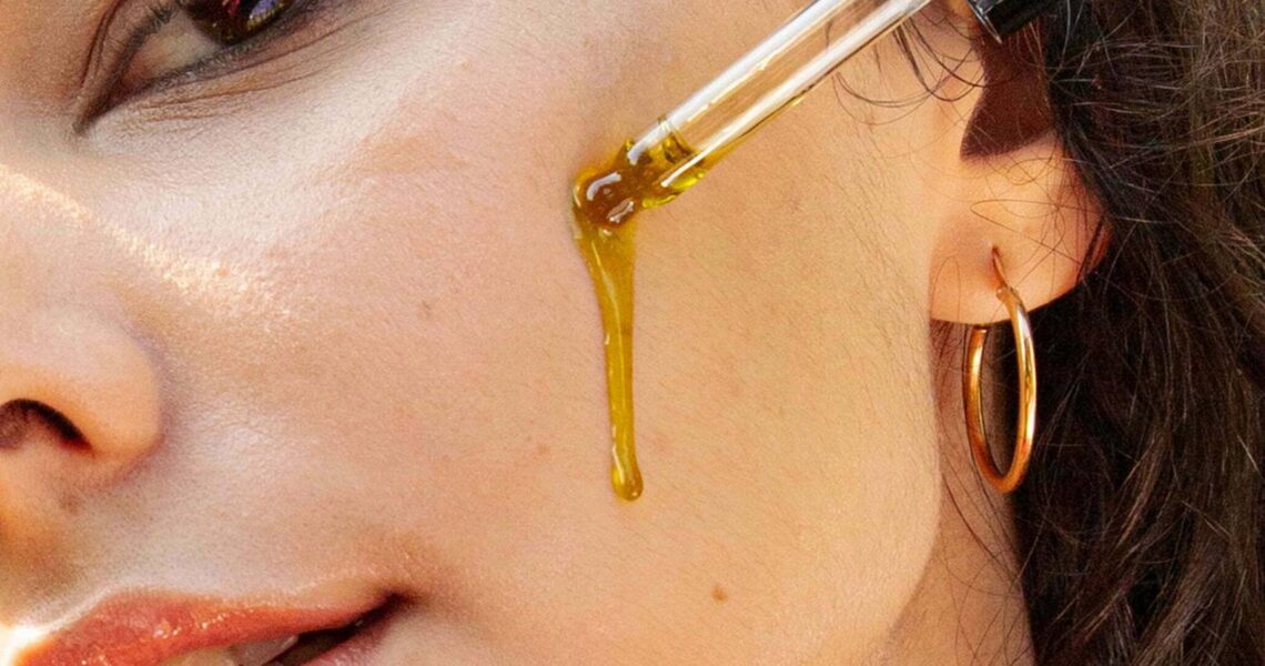 Kobieta nakłada na twarz olejek do pielęgnacji twarzy